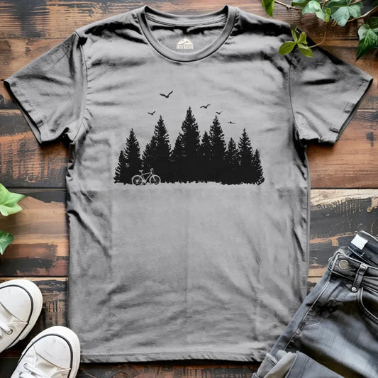 Gray t-shirt with a forest and bicycle graphic on a wooden surface