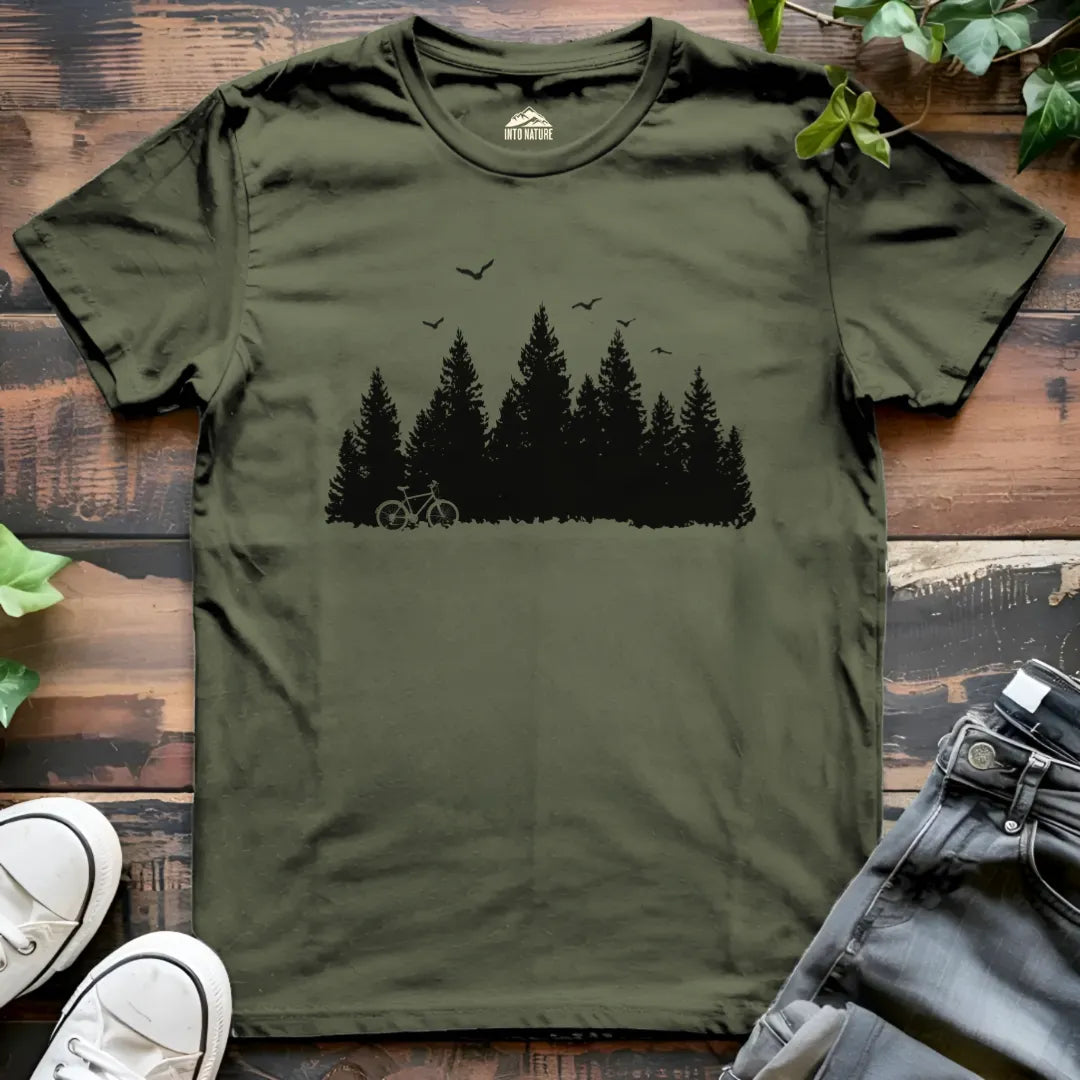 Green t-shirt with a bicycle and forest design on a wooden surface